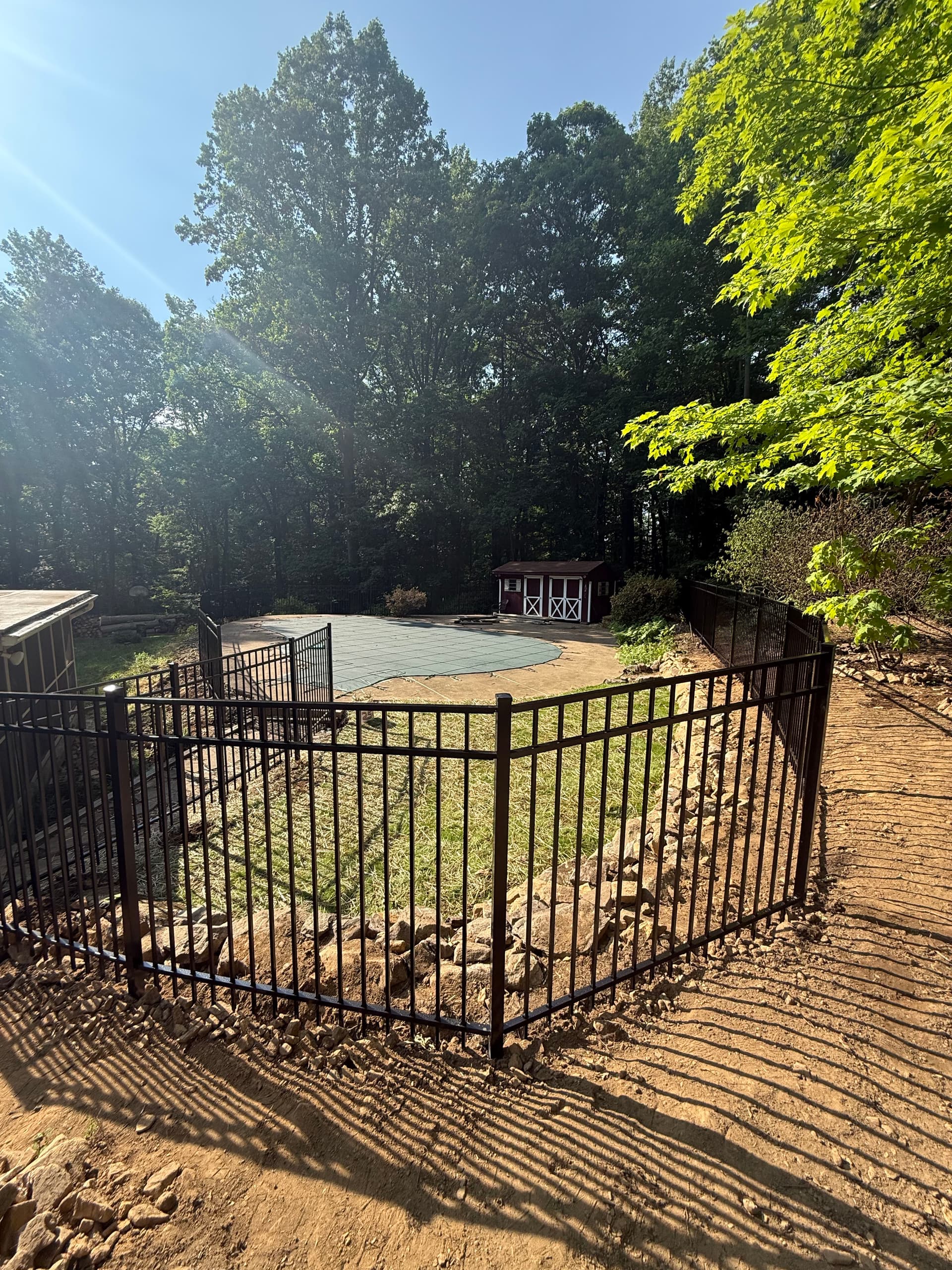 240 Feet of Black Aluminum Fencing Around a Rocky Poolside Yard image