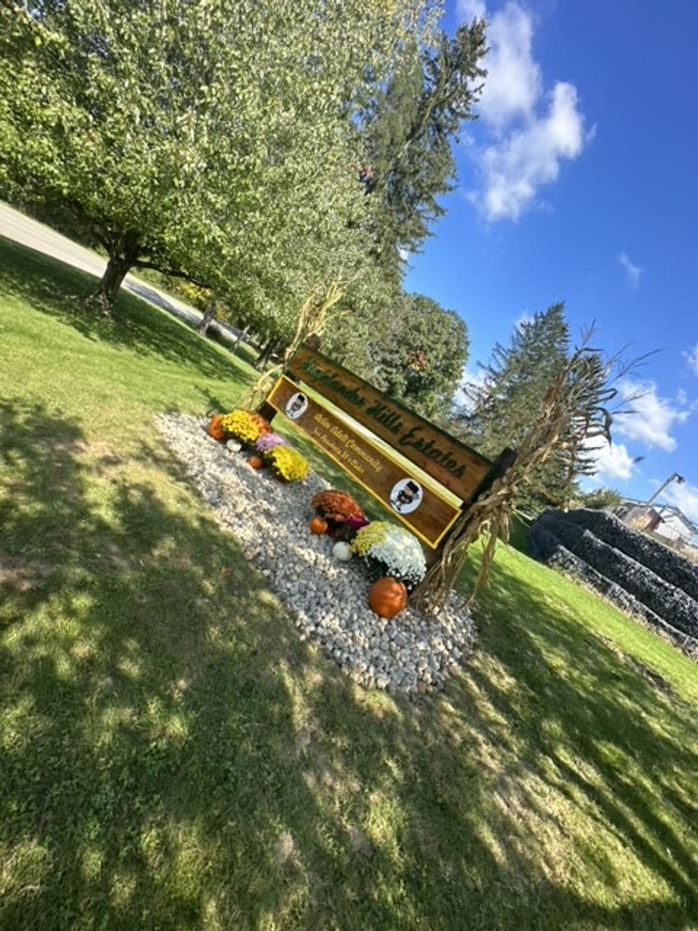 Welcome sign for Pleasant Hills Estates with fall flowers and blue sky background.